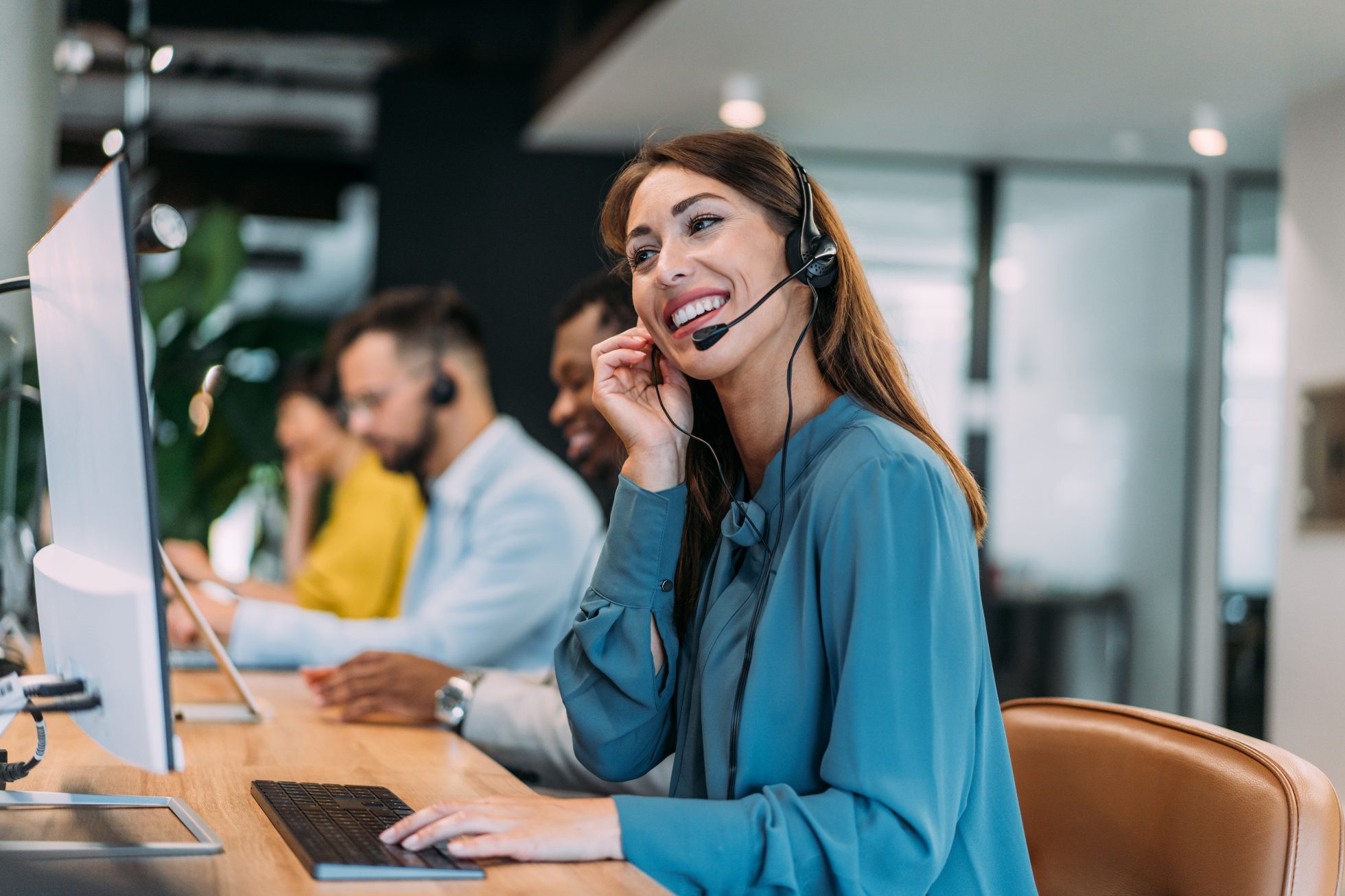 Shot of female call center agent working with her colleagues in modern office.